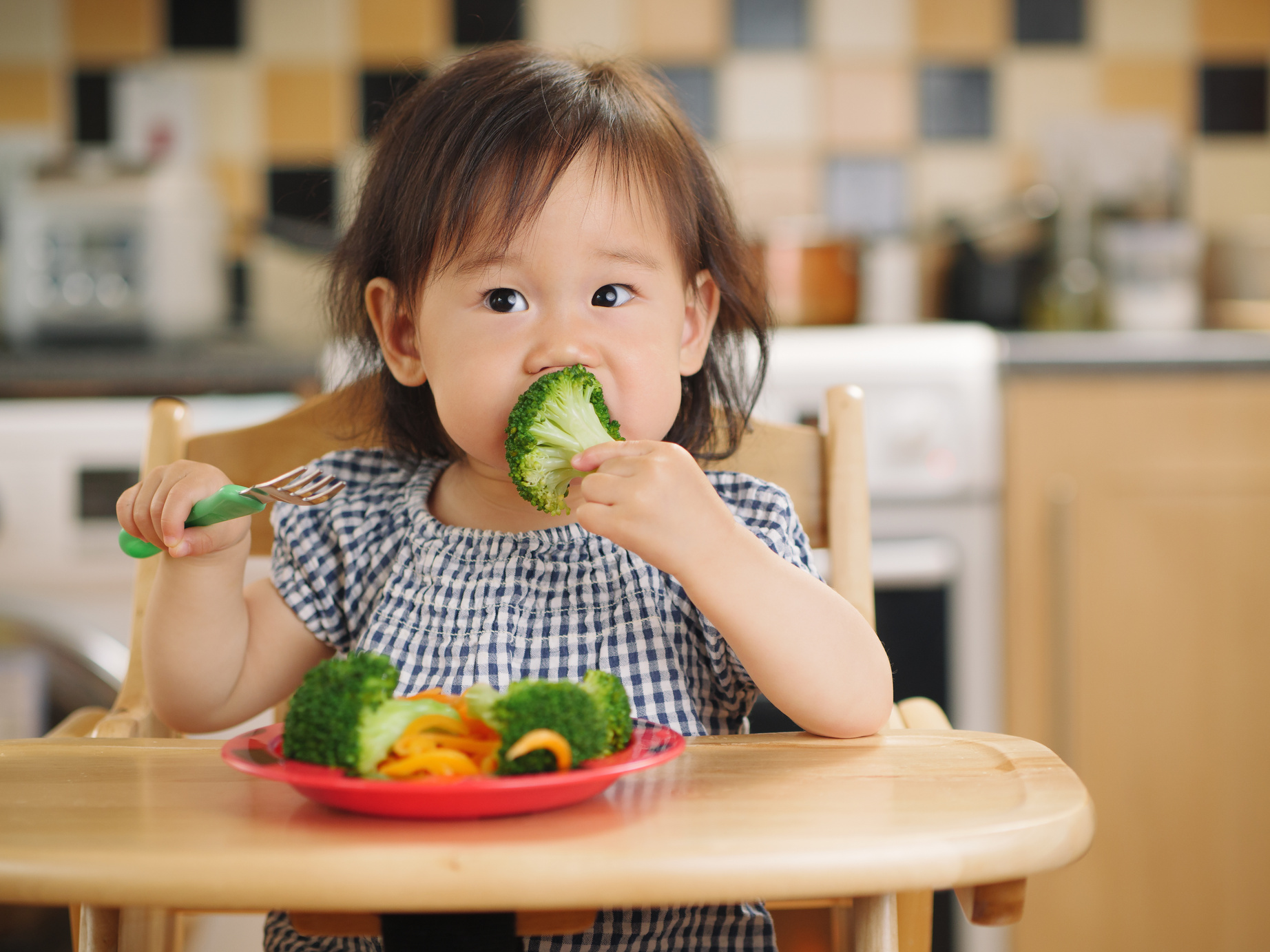 baby girl eating vegetable at home